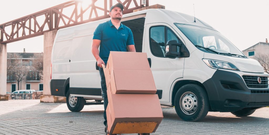 Swift Transport Services courier van with driver moving cartons on a trolley in a Melbourne street.