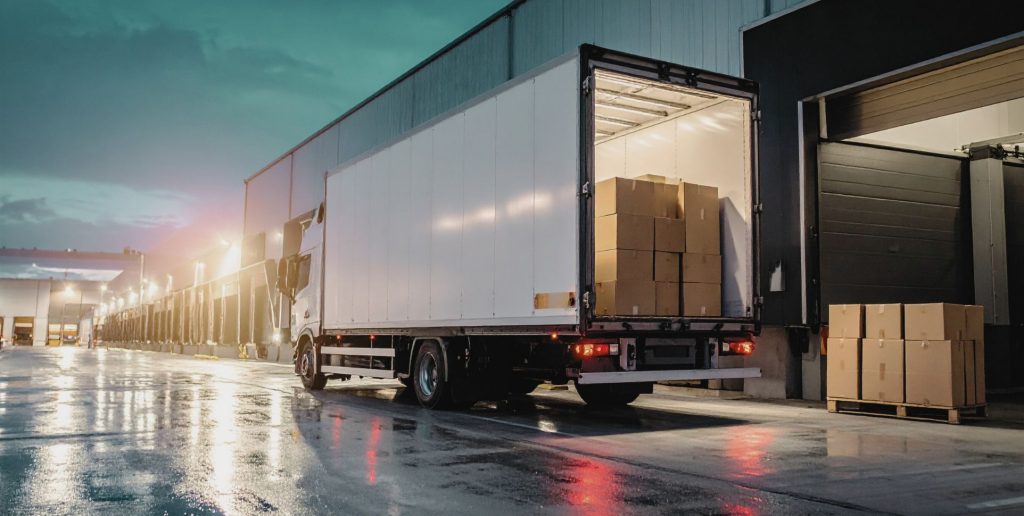 Swift Transport Services Melbourne industrial fleet lorry at dusk, rear doors open with boxes at warehouse dock. Reliable transport.